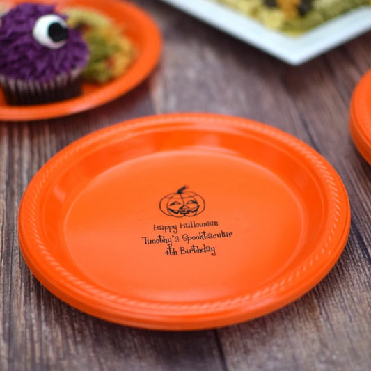 Orange plastic 7 inch plate personalized with jack-o-lantern design and 3 lines of texy in black print for Halloween birthday party