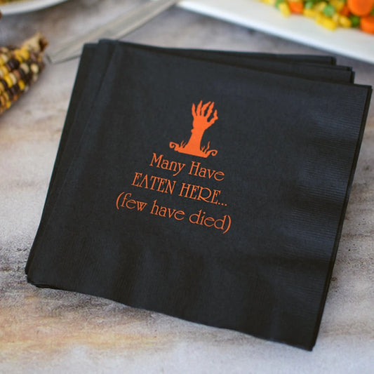 Black 3-ply paper luncheon napkins custom printed for Halloween with zombie hand design and 3 lines of text in orange print