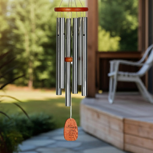 Engraved in loving memory wind chime with wooden accents hanging outdoors near porch and chair