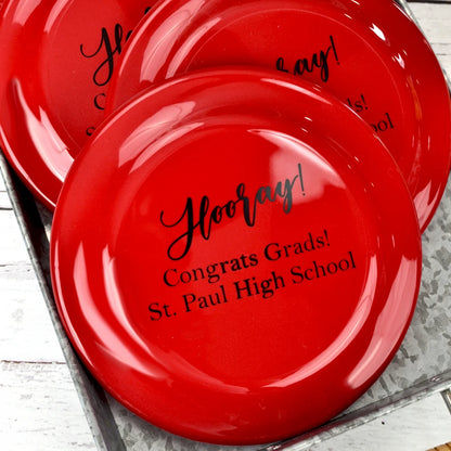 Red plastic flying disc personalized for graduation favors with "Hooray!" design and text "Gong rats Grads!, [School Name in black print