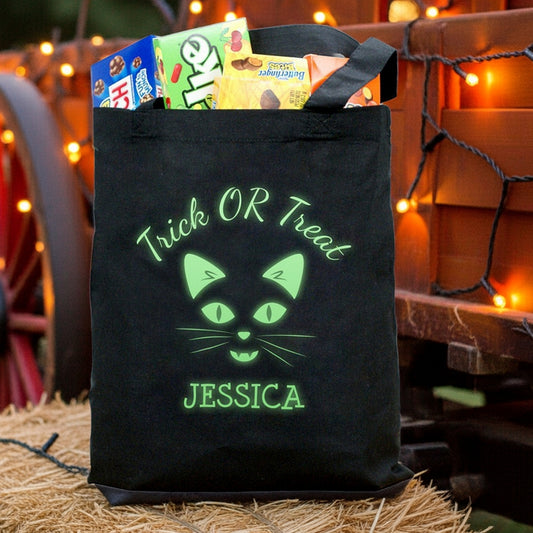 Black tote filled with candy featuring glow in the dark cat personalized trick or treat bag named Jessica with green glow