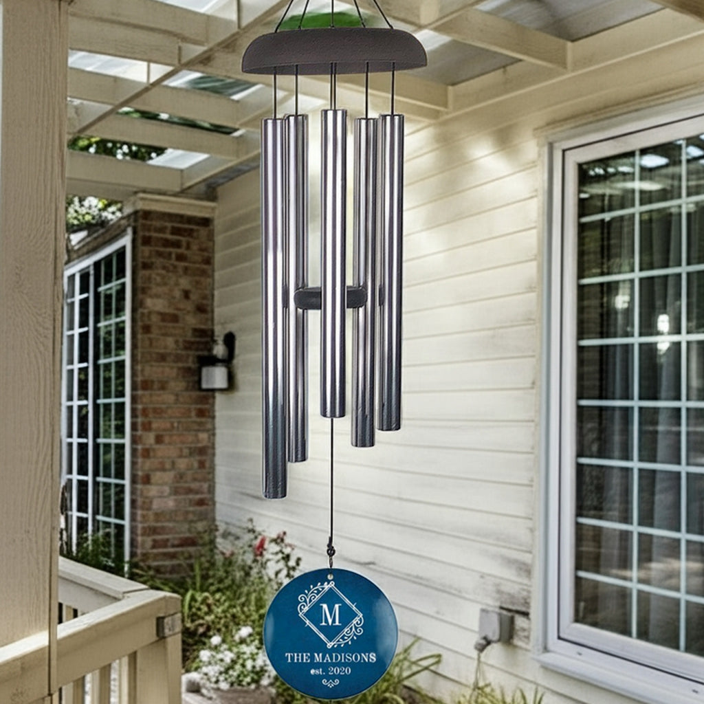 Monogram initial personalized wind chime with blue round engraved plate hanging on porch