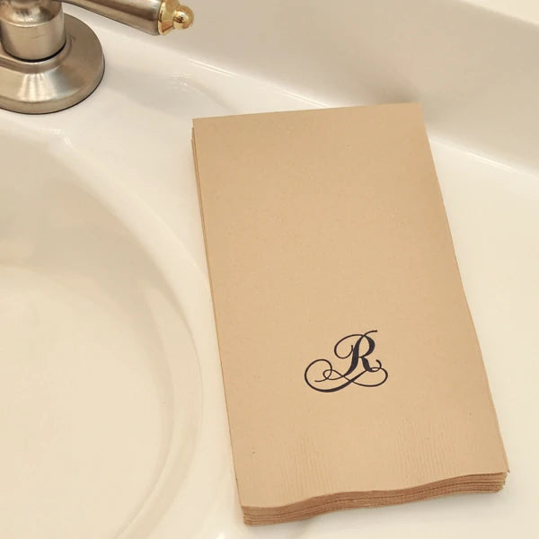 sand color disposable wedding guest towels personalized with single initial R monogram in chocolate brown print on restroom vanity sink