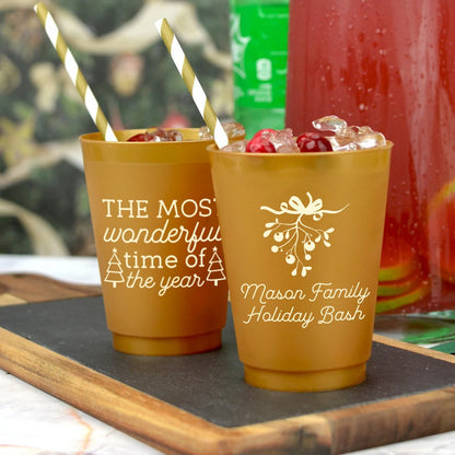 Gold plastic holiday party cups personalized with Mistletoe design and text on front side and  The Most Wonderful Time of the Year design on back side in ivory print