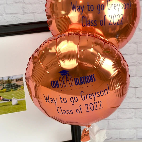 Rose gold color round mylar graduation balloons personalized with congradulations design and custom text in navy print