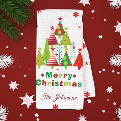Personalized Christmas kitchen hand towel featuring festive trees and Merry Christmas text with custom family name