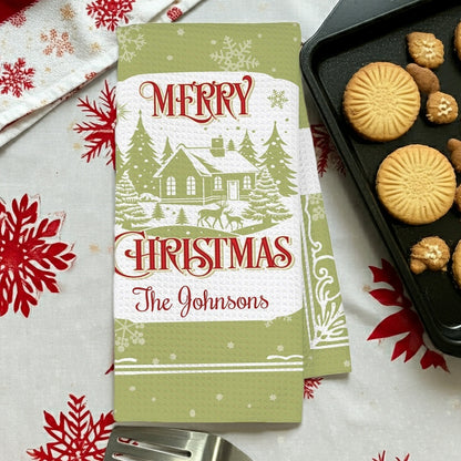 Personalized Christmas kitchen towel featuring a festive design with a snowy house and the name The Johnsons