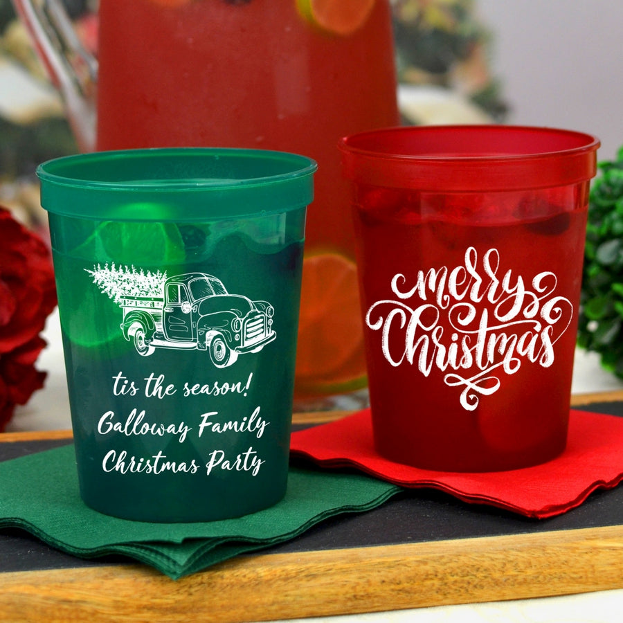 translucent green 16 Oz. stadium cup personalized with 'Vintage Christmas Truck' design and three lines of custom text in white imprint color and Translucent Red cup personalized with 'Merry Christmas Calligraphy' design in white imprint color