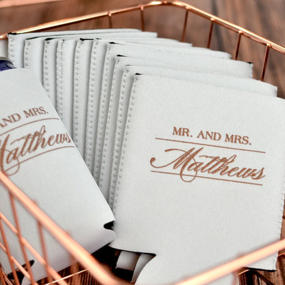 White color waterproof neoprene wedding can coolers personalized with mr and mrs text and married couple last name in gold print for reception guest favors
