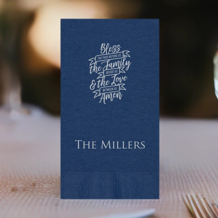 A navy color paper one-eighth fold dinner napkins personalized with bless the family deisgn and family name in silver print