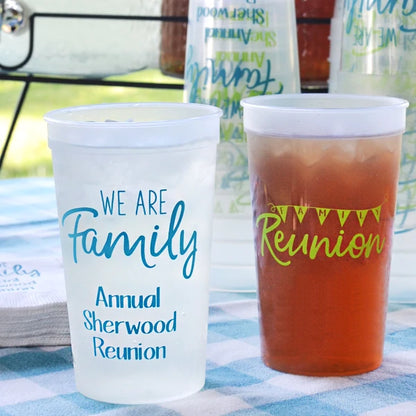 Clear 22 ounce family reunion stadium cups personalized with we are family design and 3 lines of text on front side and family reunion banner design on back side in cornflower blue print on picnic table