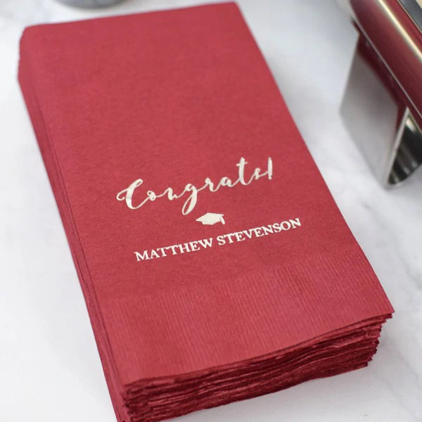 Burgundy color disposable graduation guest hand towels personalized with congrats grad cap design and graduate name in silver print