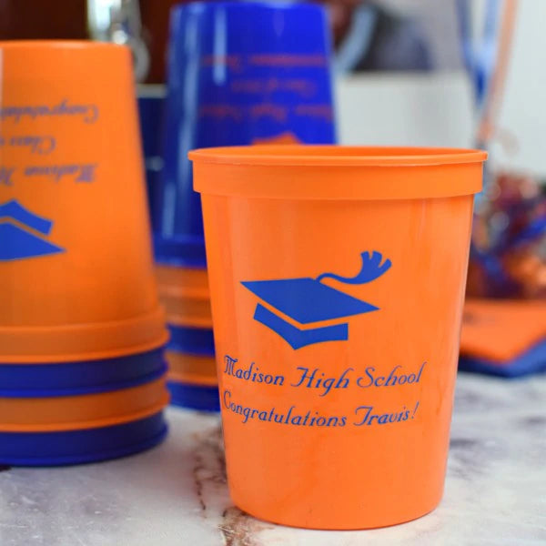 Orange color graduation stadium cup personalized with grad cap design and 2 lines of text in blue print