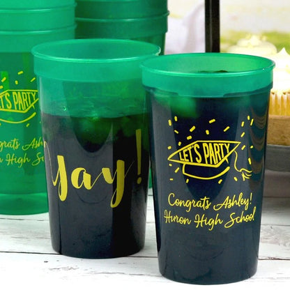 Translucent green color 22 oz. graduation stadium cups personalized with lets party grad cap design and 2 lines of text on the front and yay! design on the back in yellow print