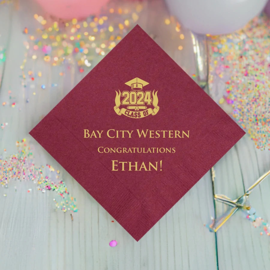 burgundy graduation party drink napkins personalized with class of 2024 bold ribbon design and 3 lines of custom text in gold print