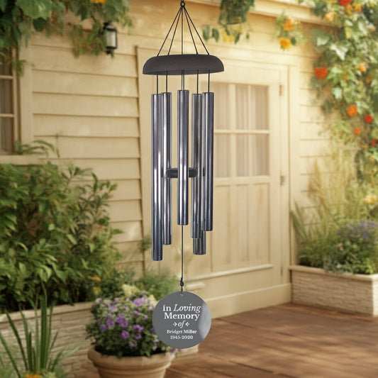 In loving memory personalized memorial wind chime hanging outdoors near plants and a wooden door