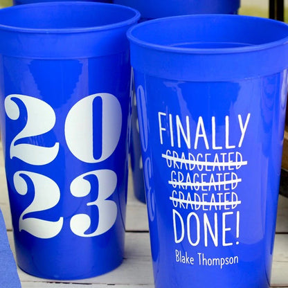 Blue color 32 oz. graduatoin party stadium cups personalized with finally done! design and 1 line of custom text on the front and 2023 design on the back in white print