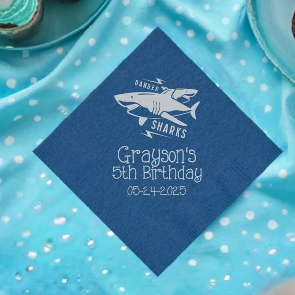 Cobalt blue color boys birthday napkin personalized with danger sharks design and 3 lines of text in silver print