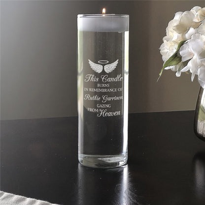 Personalized memorial candle with angel wings and remembrance message burning on table