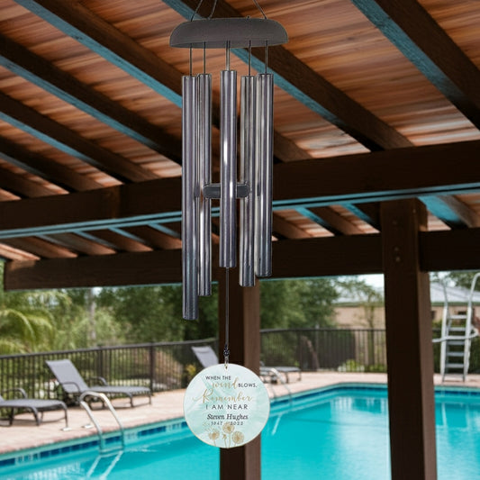 Personalized memorial wind chime hanging near poolside under patio roof