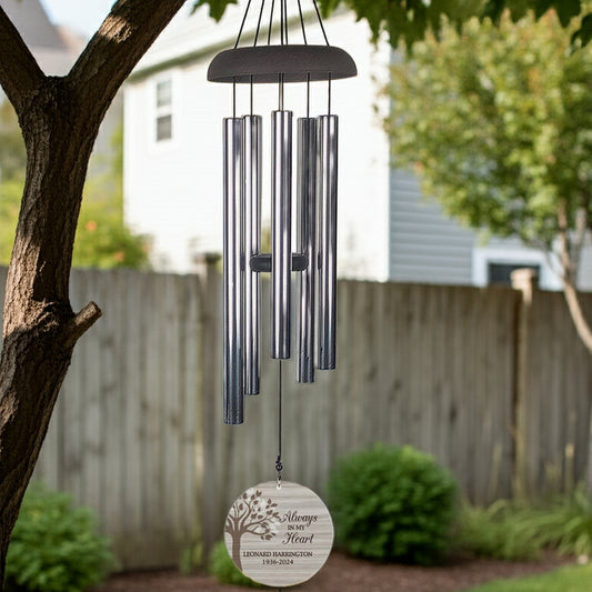 Personalized memorial wind chime hanging from tree with engraved round wooden pendant