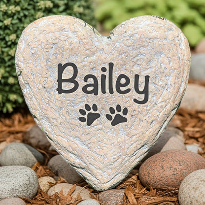 Heart-shaped personalized pet memorial stone with pet name Bailey and paw prints in garden setting