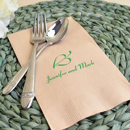 ivory color 1/8 fold wedding dinner napkin personalized with leaf heart design and bride and groom names in green print on table placemat with silverware