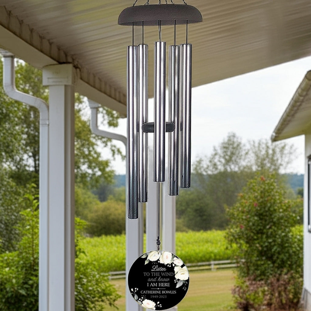 Personalized wind chime memorial with silver tubes and engraved floral ornament hanging on porch