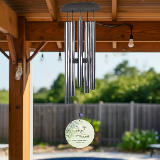 Personalized wind chime memorial hanging under wooden pergola with engraved tribute charm