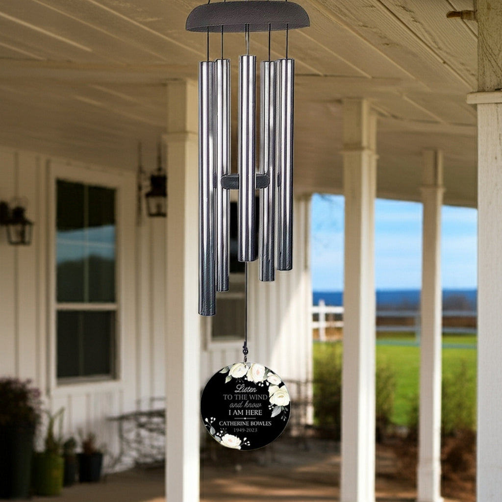 Personalized wind chime memorial with silver tubes and floral engraved message hanging on porch