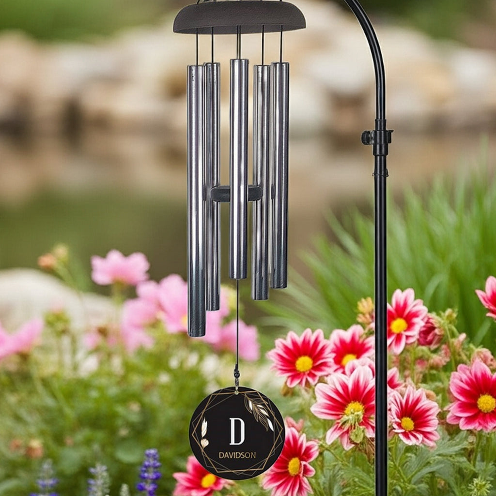 Personalized wind chime with metal tubes and custom engraved black pendant in garden setting