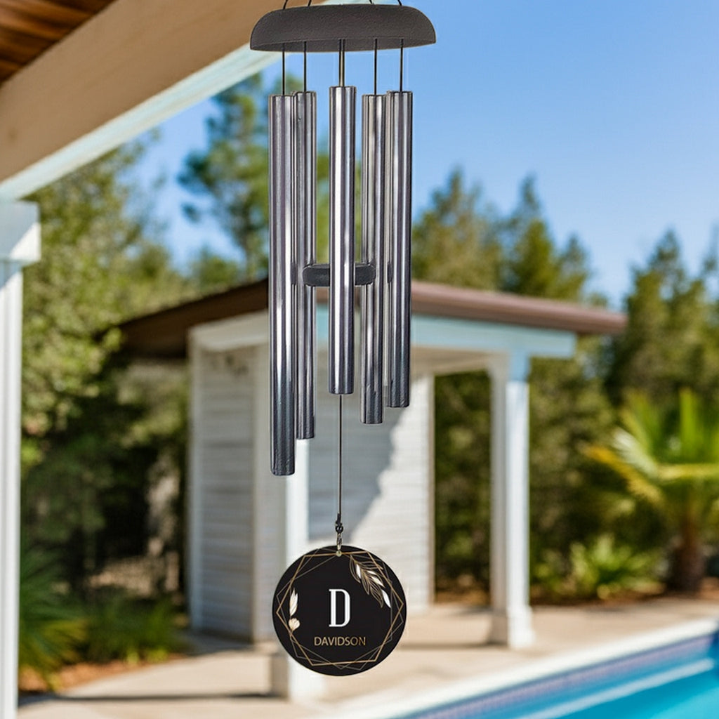 Personalized wind chime with metal tubes and custom name tag hanging outdoors by pool