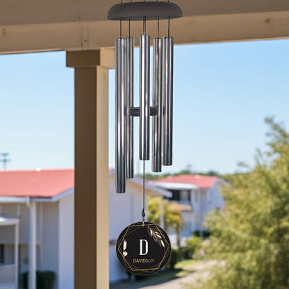Personalized wind chime with silver tubes and custom monogrammed black pendant hanging outdoors