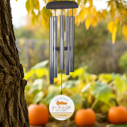 Personalized wind chime with metal tubes hanging outdoors near autumn pumpkins
