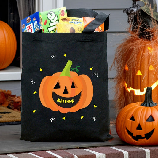 Black tote with pumpkin personalized trick or treat bag design featuring smiling jack o lantern and candy on porch