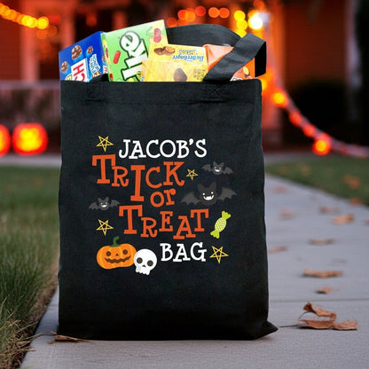 Black Halloween pumpkin skull and bats personalized name trick or treat bag filled with candy on lit path