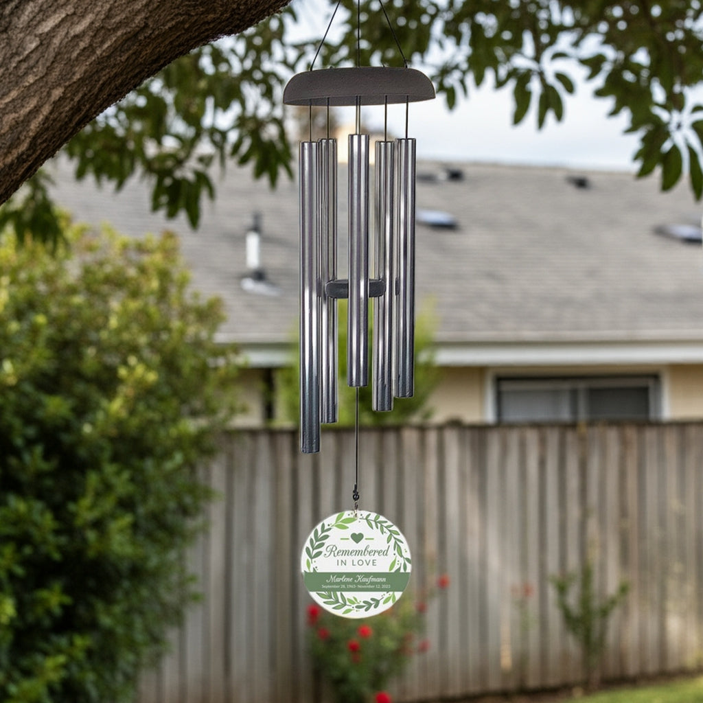 Remembered in love personalized wind chime hanging from tree branch in backyard
