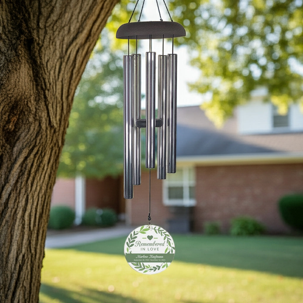 Remembered in love personalized wind chime hanging from a tree in a sunny backyard setting