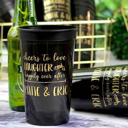 Black 22 oz. stadium wedding cups personalized with happily ever after design and bride and groom name in gold print at wedding drink station