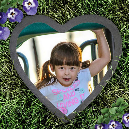 Slate heart photo garden stone with a child's picture surrounded by green grass and purple flowers