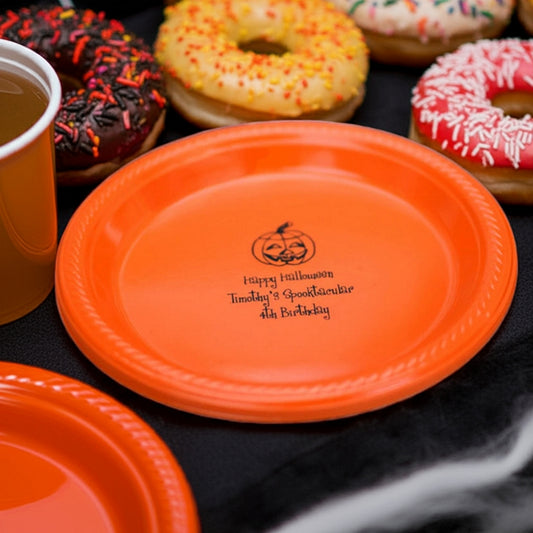 Orange plastic plate with jack o lantern and custom text beside donuts personalized plastic Halloween appetizer and dessert plates