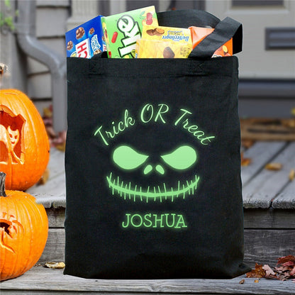 Black tote with glowing green monster face and Joshua filled with candy glow in the dark monster personalized trick or treat bag