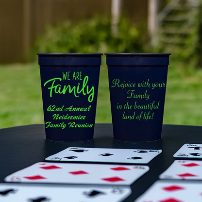 Two navy cups personalized for family reunion favors with "We Are Family" graphic, and custom text on the front and back side in neon green print