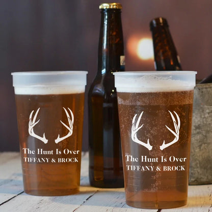 Clear 22 oz. stadium cups personalized with antlers design and the hunt Is over text with bride and groom names in ivory print