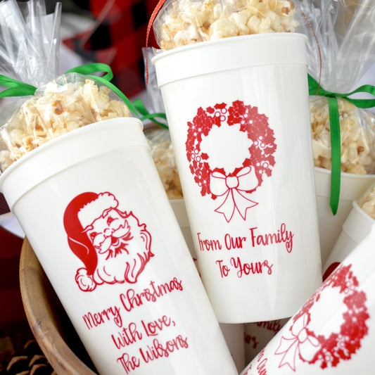 White extra large 32 oz stadium cups personalized for Christmas party favors with santa and wreat desin and custom text in red print