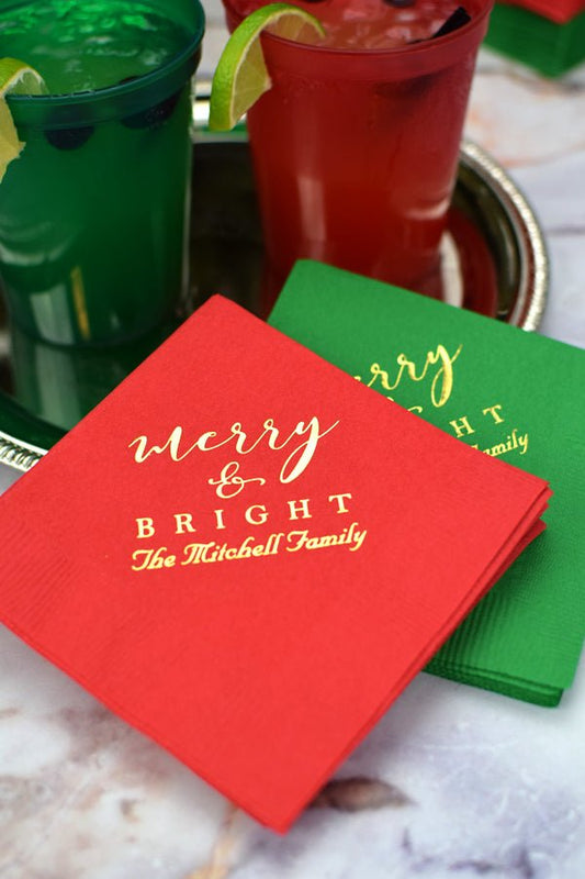 Red and green 5 x 5 cocktail beverage napkins personalized with 'Merry & Bright' holiday design and 1 lines of custom text in gold imprint color for christmas party drinks